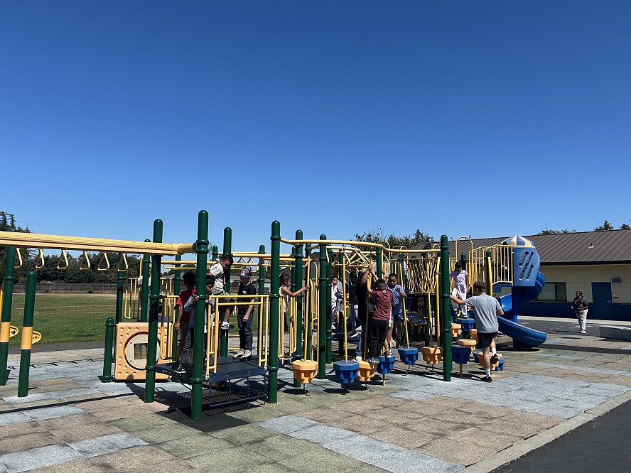 Children playing on a play structure at a school playground.