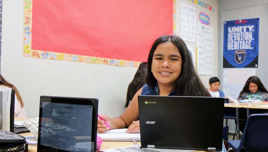 middle school girl smiling with laptop in front of her