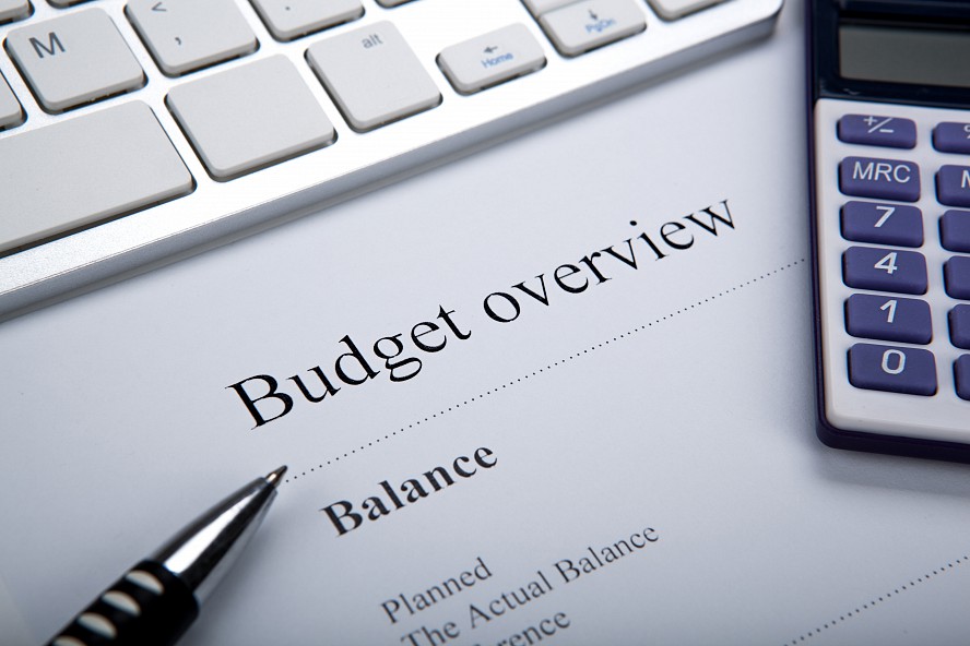 budget report showing tables of numbers, next to a calculator and a pen