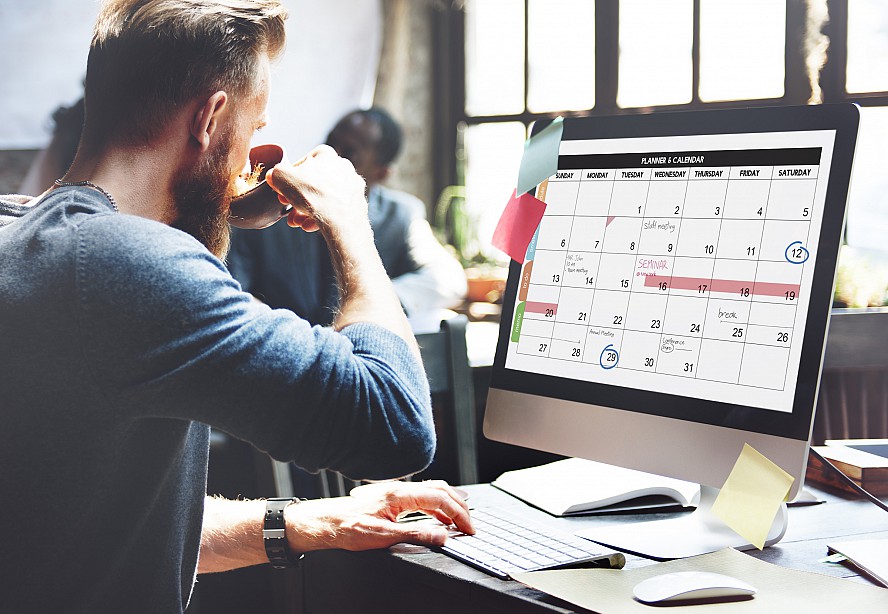 man at computer with calendar