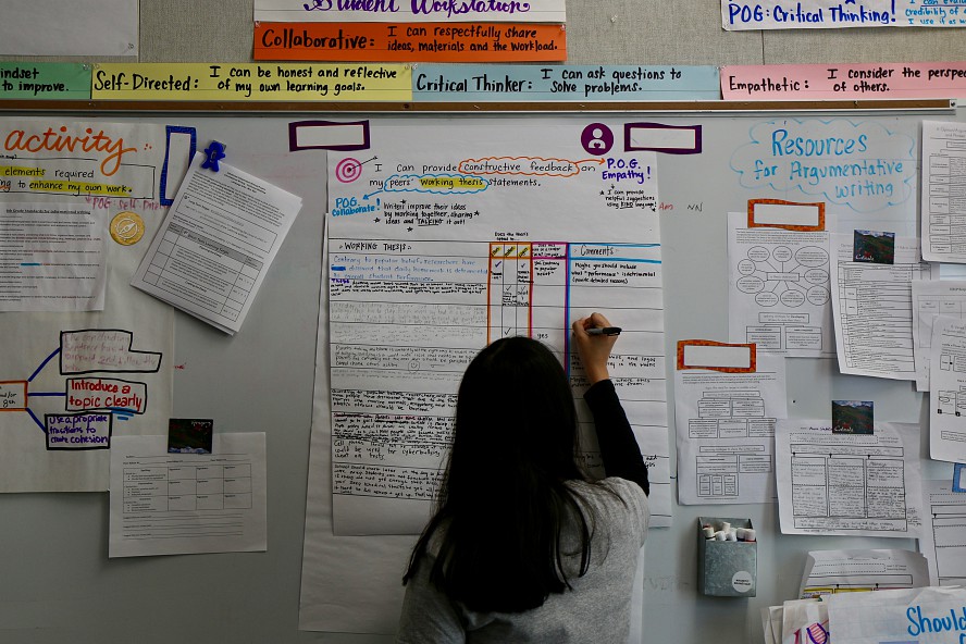 middle school girl writes on a chart describing the plan for a project