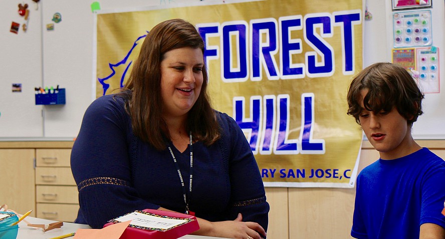 teacher with student. sign behind says forest hill