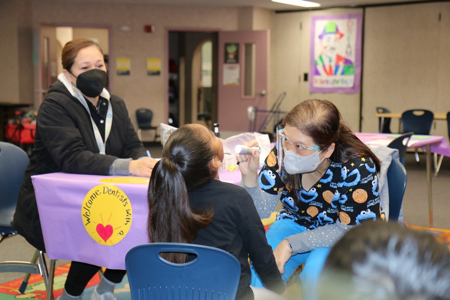 Woman looks on as dentist looks into a child's mouth