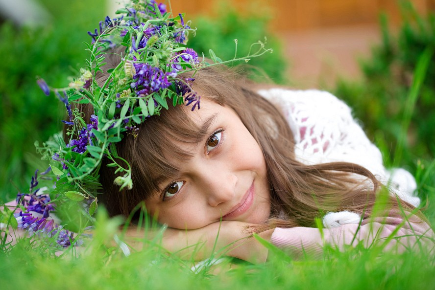 smiling young girl resting on grass and flowers