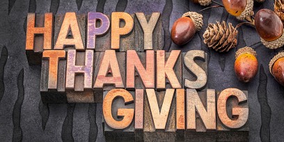 acorns and the words: Happy Thanksgiving on a wooden board
