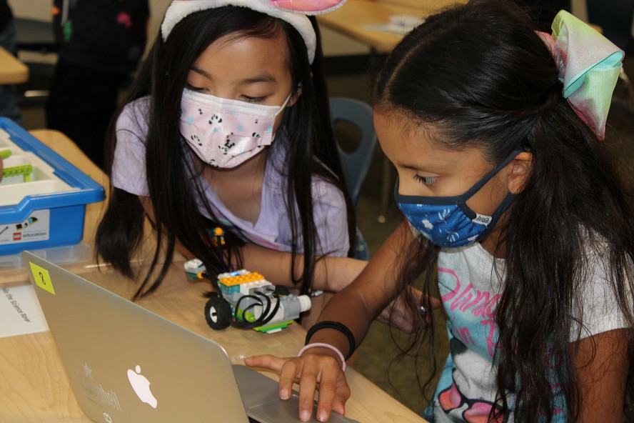 two girls work together on a coding project