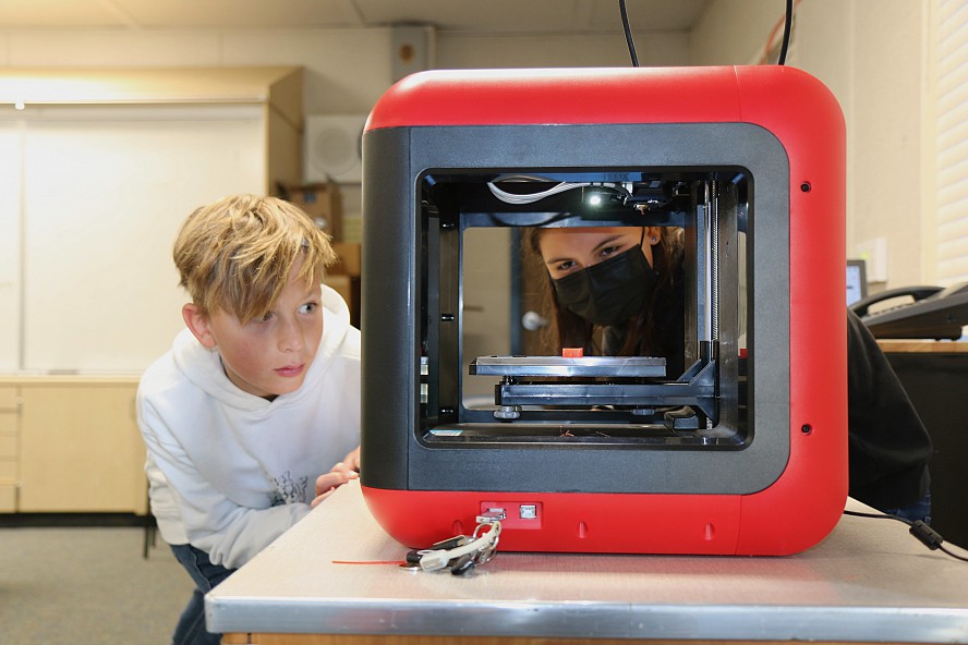 students looking at a 3-D printer