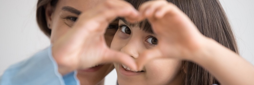 little girl smiling through hand shaped like a heart