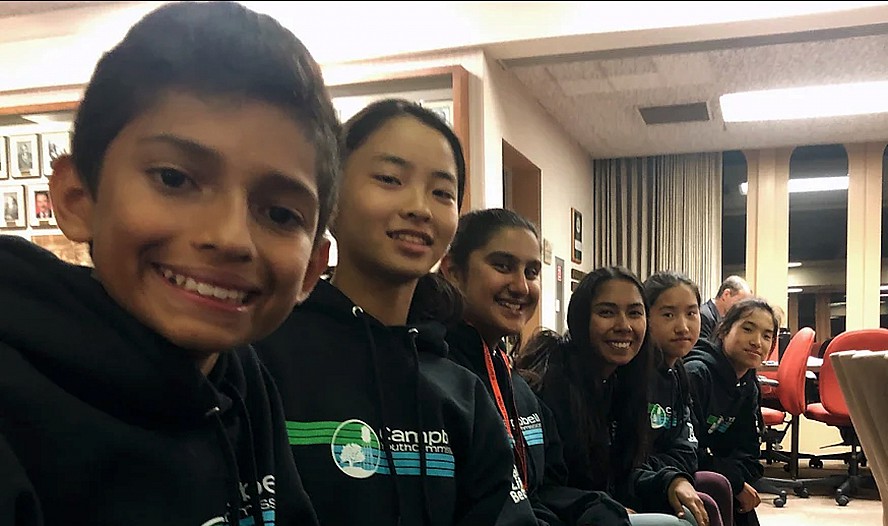 girls and boys sitting in a row and smiling at the camera