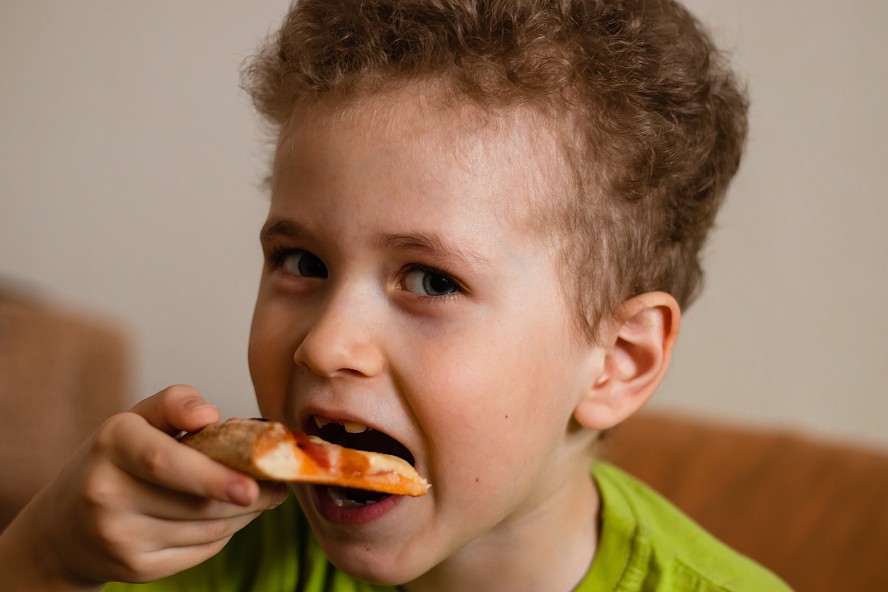 boy biting a pizza slice
