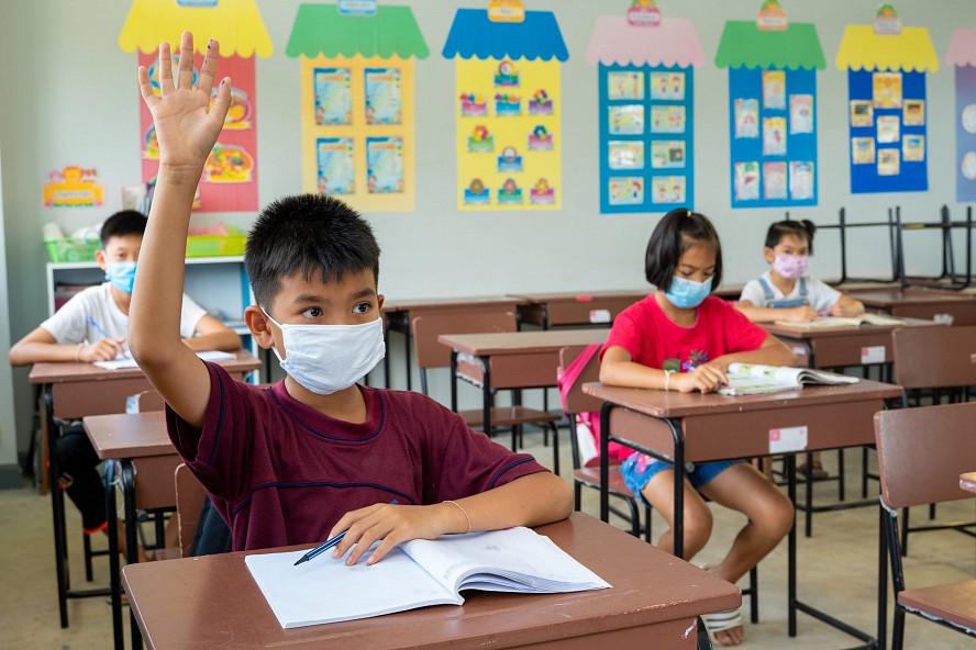 boy raising hand in class social distancing