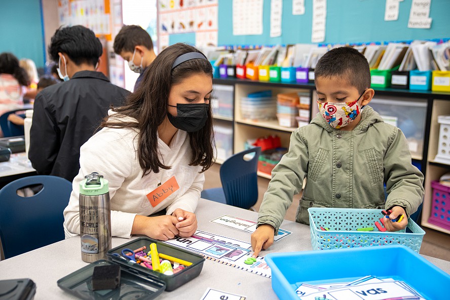 older student works with younger boy on spelling