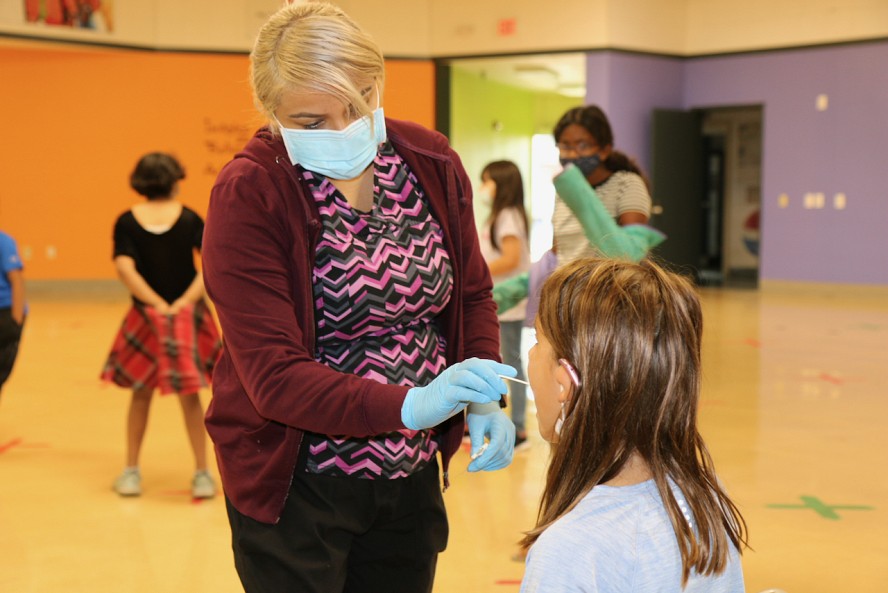 health worker swabs a student's mouth as part of the COVID-19 testing