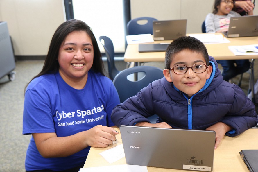 college student works with young boy at computer