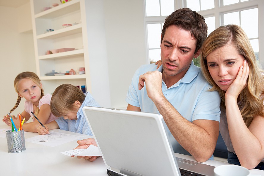 parents looking puzzled at laptop as students work at table