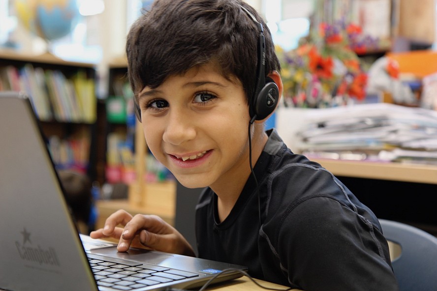 smiling boy with computer and headphones