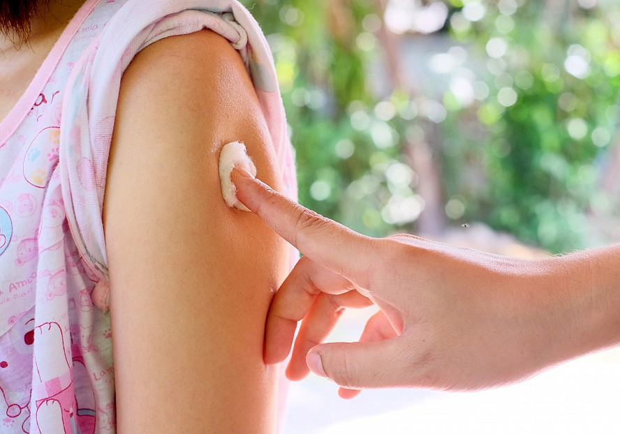 child's arm with adult holding cotton ball in place