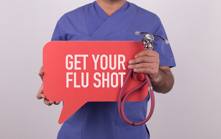 man holding a sign saying get your flu shot