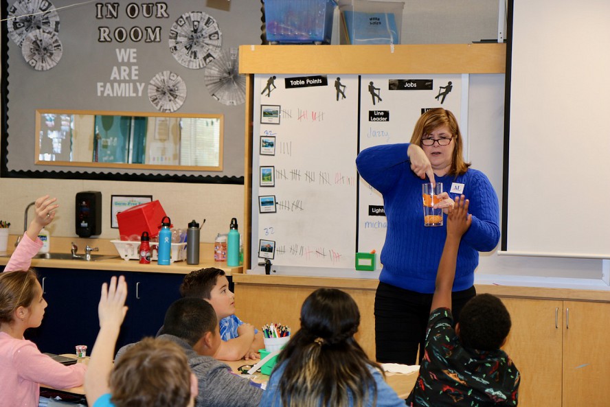 woman in front of students demonstrating lesson