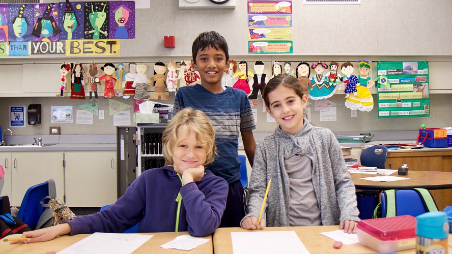 smiling students writing at a desk