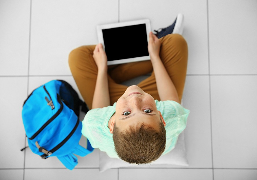 young boy holding tablet and looking up