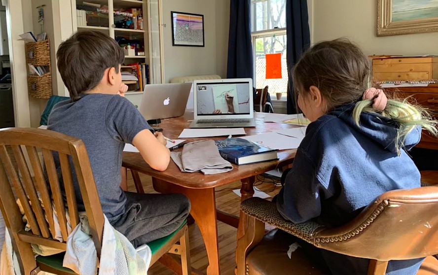 2 students at kitchen table with laptops distance learning