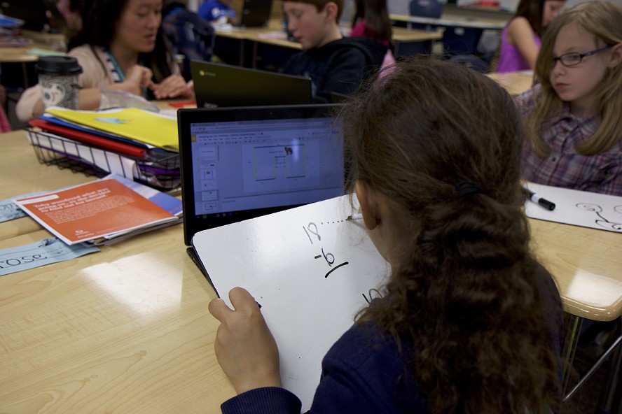 child writing a math problem in class