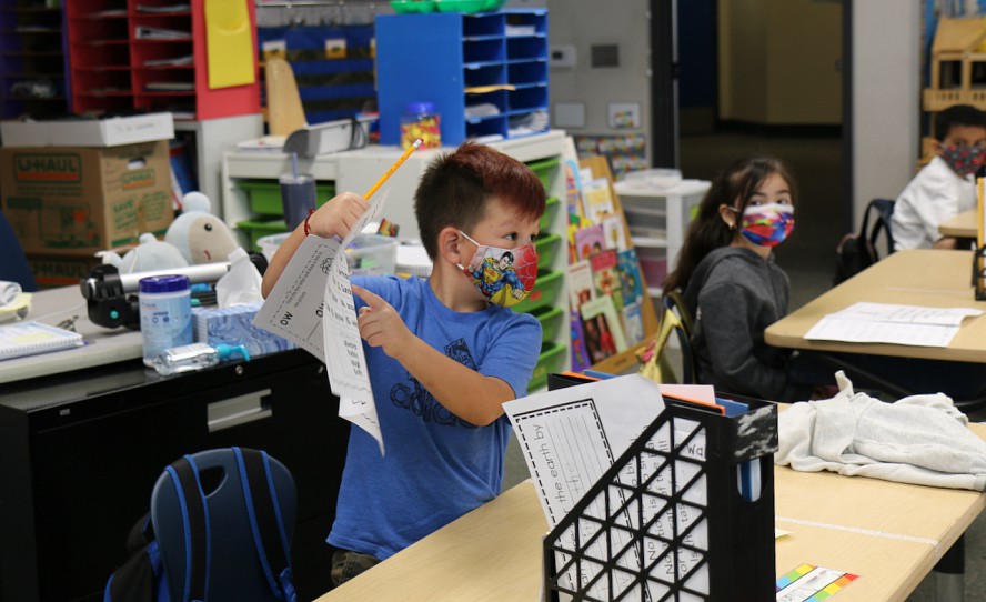 boy holding paper up in class