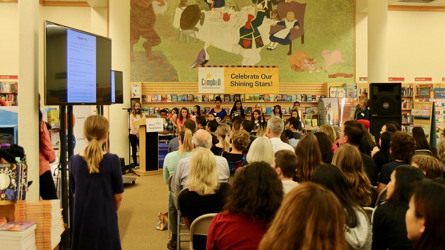 audience listens to a 2018 student author at podium