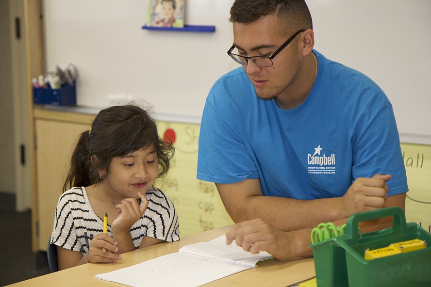 student works on homework with after school staff