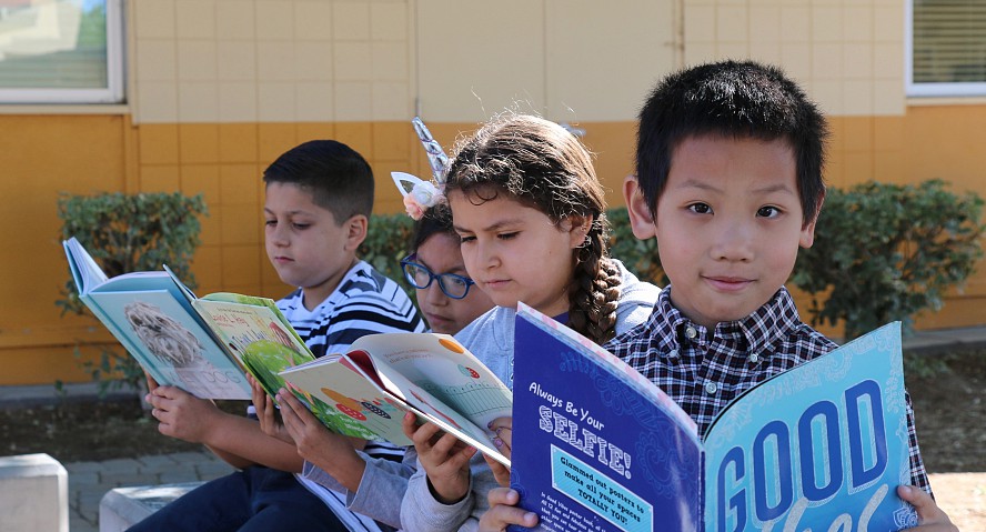 four children reading outside