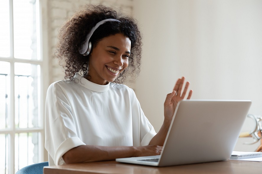 woman teacher waves to students on laptop