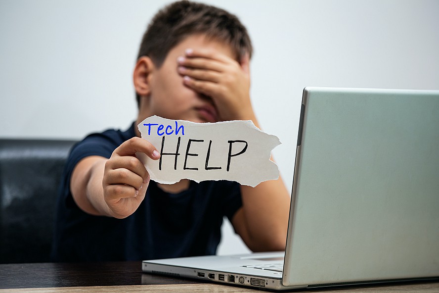 boy at laptop holding sign that says Tech Help