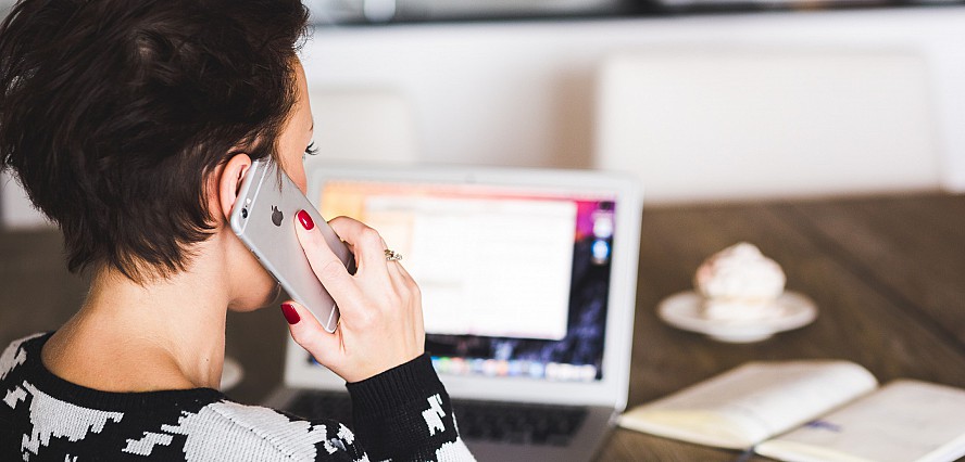 woman talking on phone while at the computer