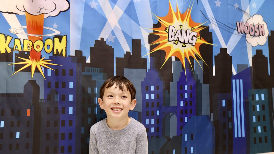 little boy standing by painting of skyscrapers and fireworks