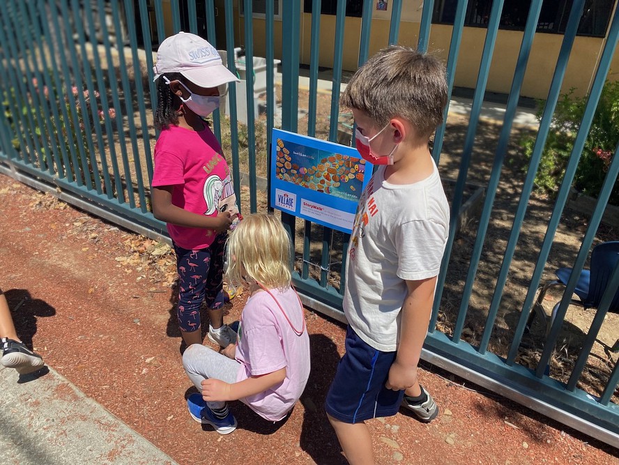 children read a page of a story posted on a fence