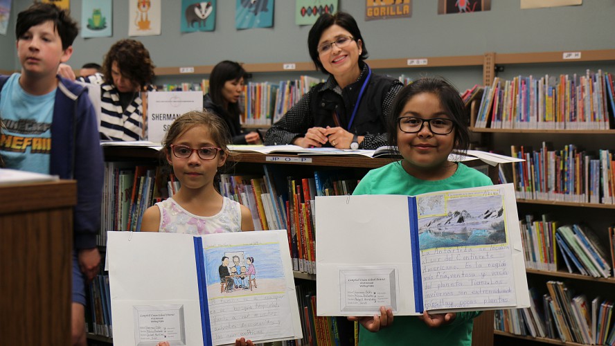 students showing books and smiling