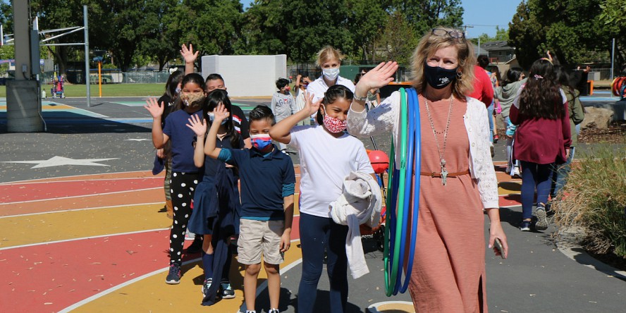 teacher and students on playground waving hello