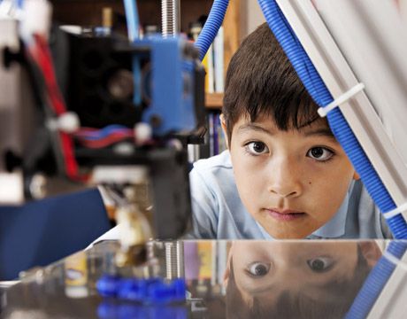 boy looks as 3-d printer works