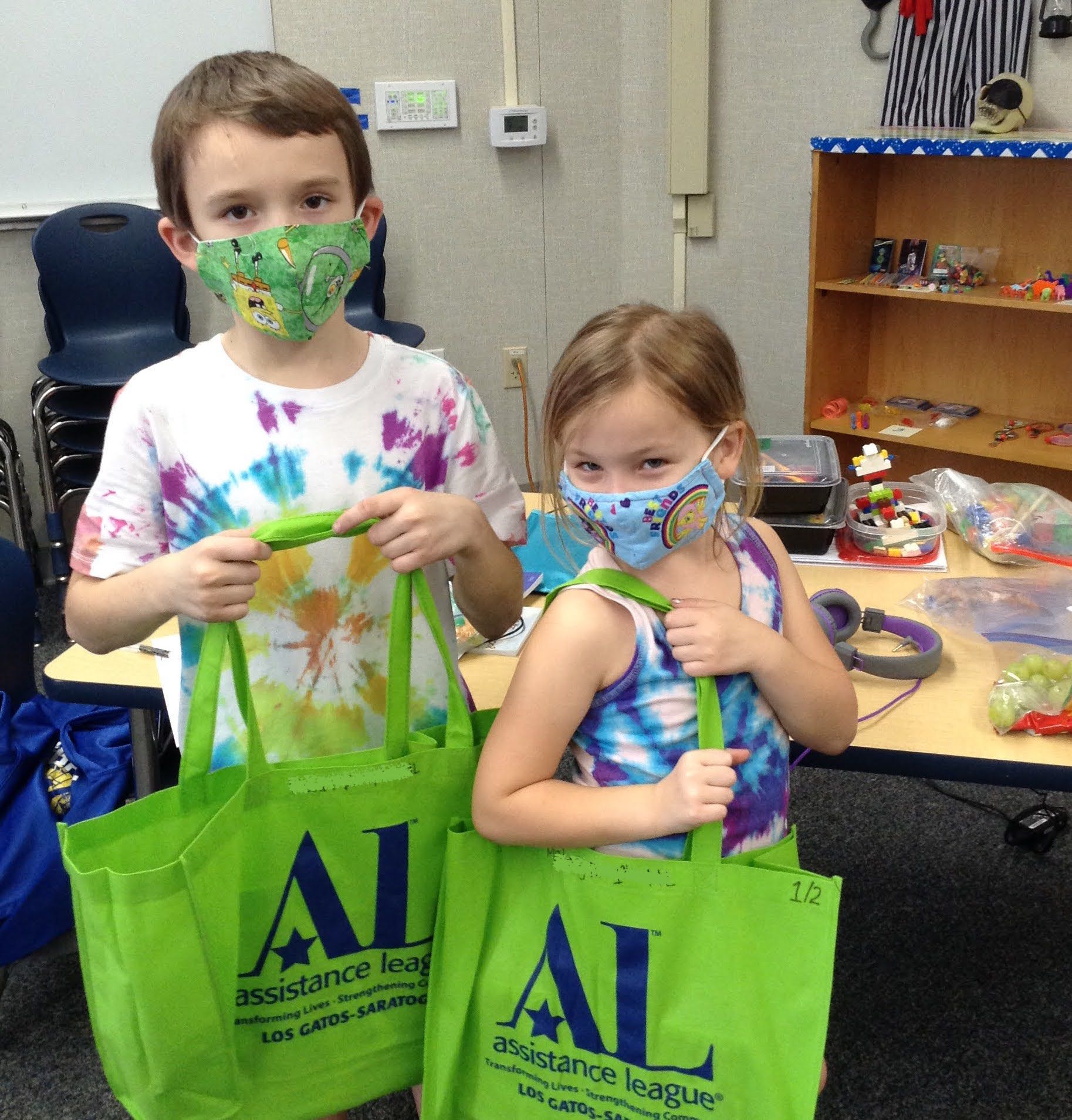 two students wearing masks and showing new kit bags