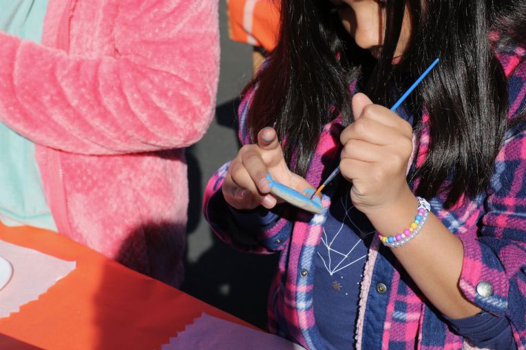 close up of girl using paintbrush to pain a rock