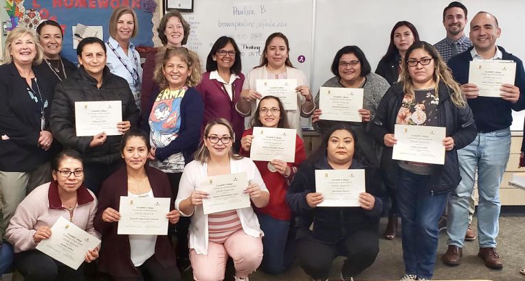 pre-pandemic photo of a group of adults holding graduation certificates