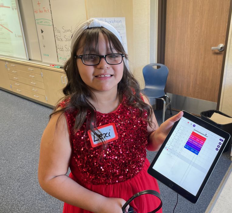 girl in glasses smiling and holding ipad