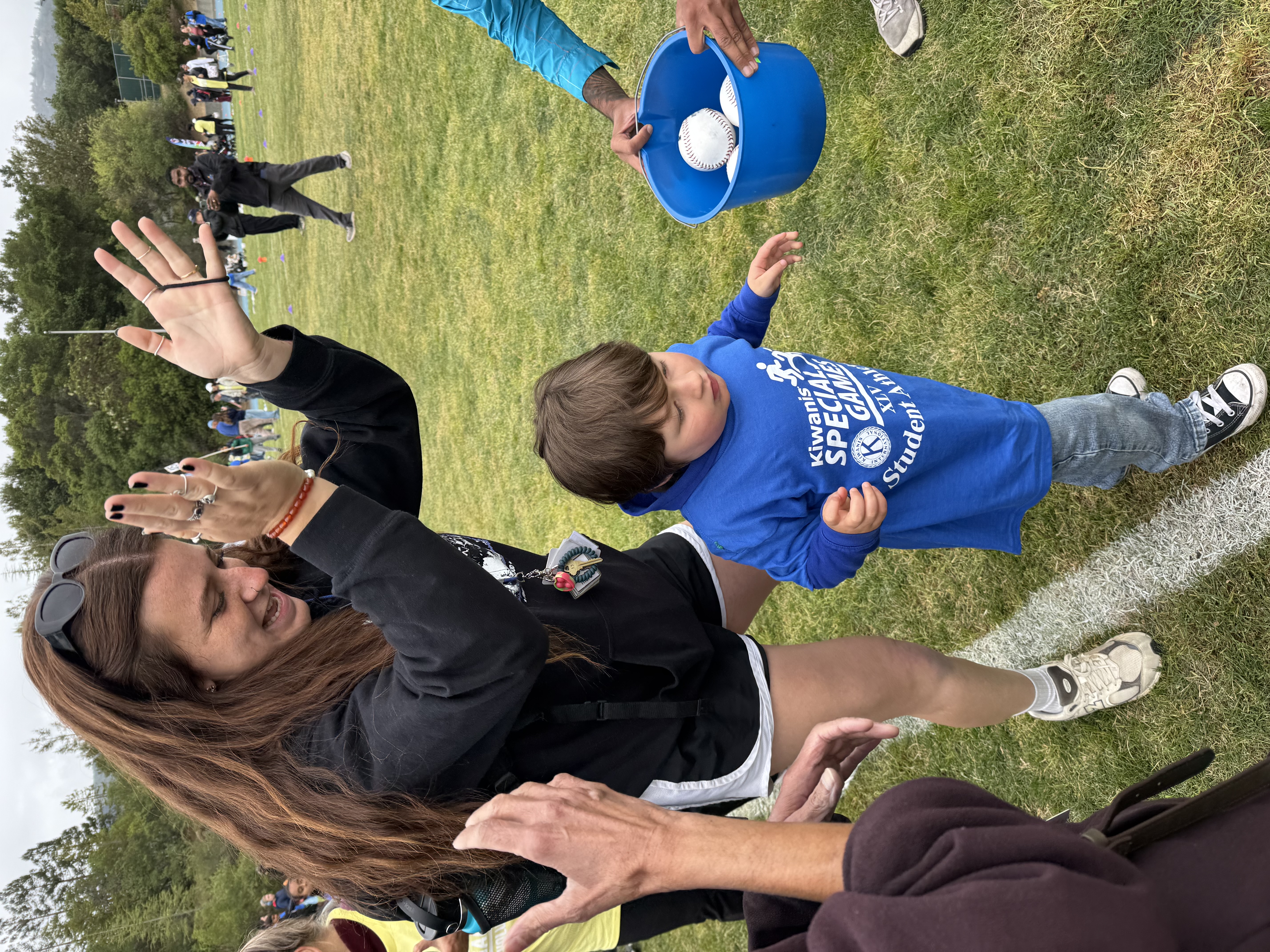woman cheers and claps for a preschool-aged child running before her.
