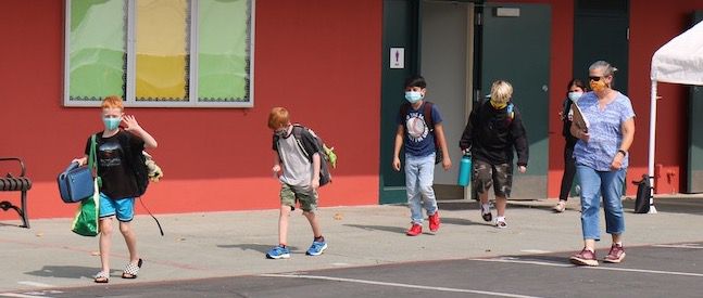 students in masks walk through campus