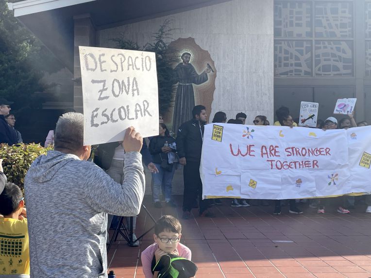 people holding signs about driving slower