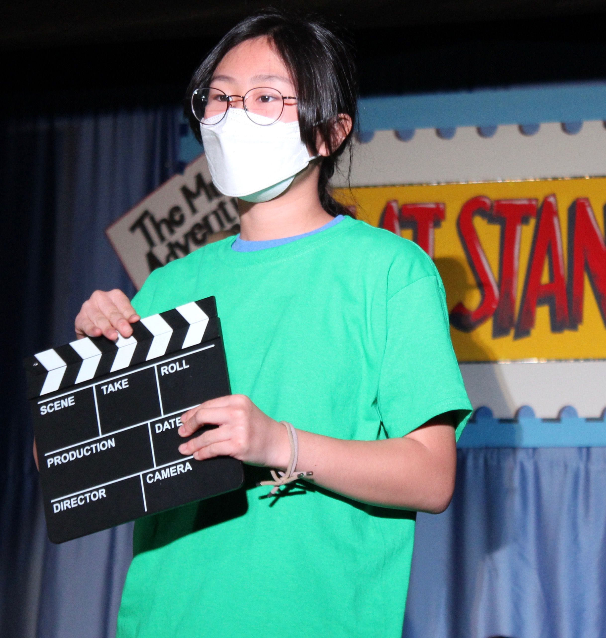 girl in school play holding a scene slate