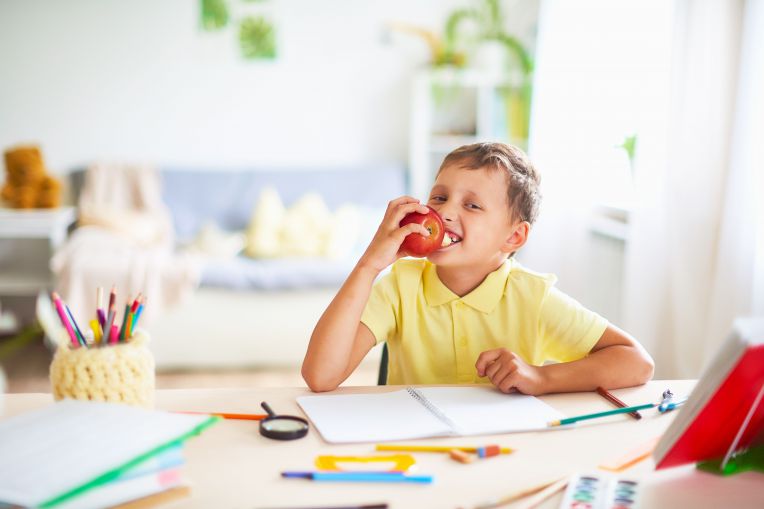 boy eating apple while doing homework