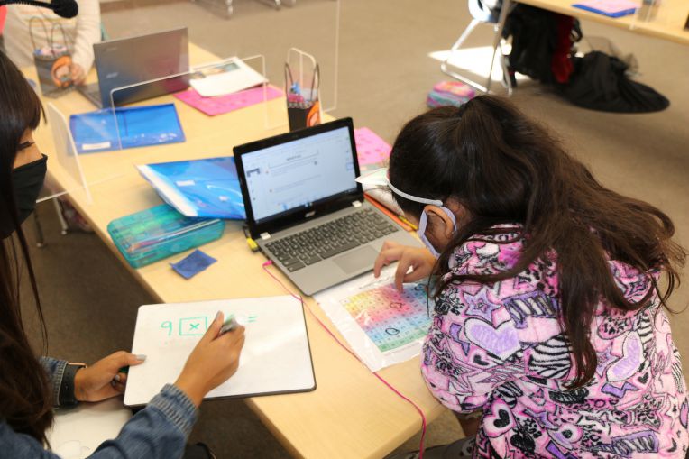 student working on math problem with help from teacher