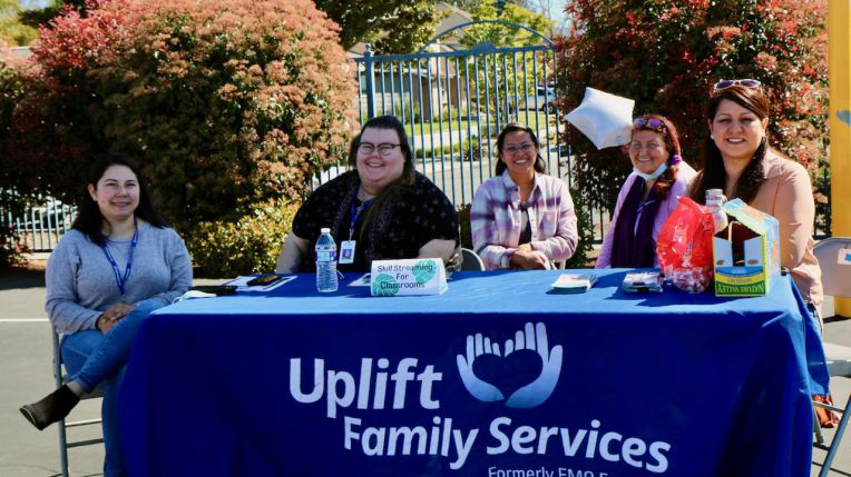 staff at table with sign reading Uplift